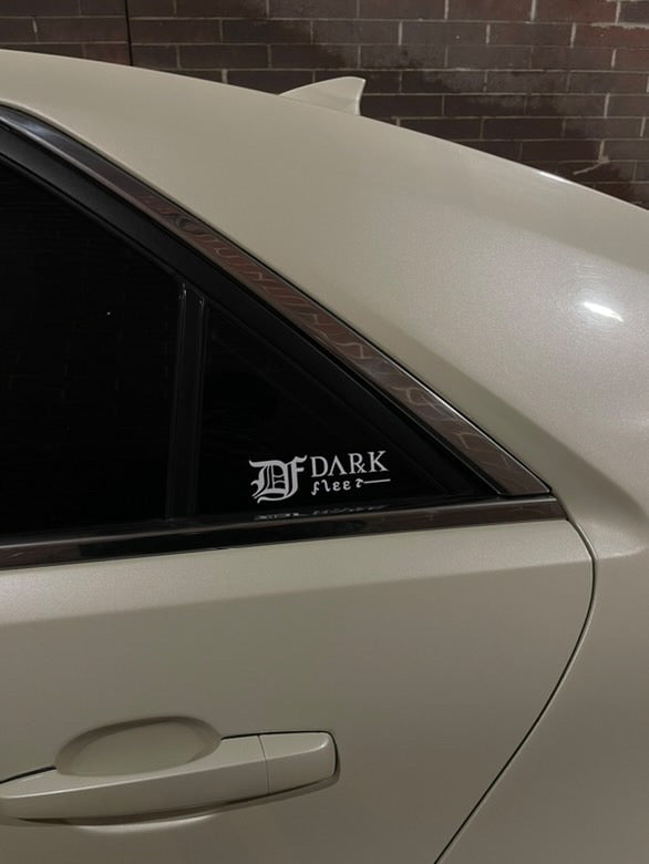Car window with a 'Darkfleet' decal against a brick wall background