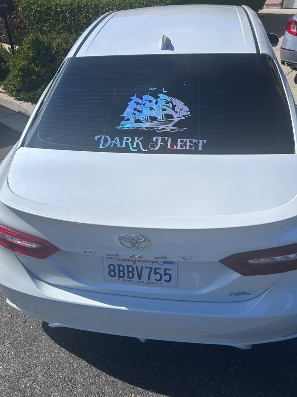 Car with 'Dark Fleet' logo on the back window, parked outdoors.
