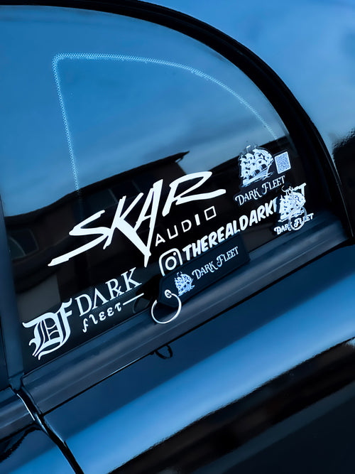 Car window with multiple stickers including 'SKAR Audio' and 'Dark Fleet'.