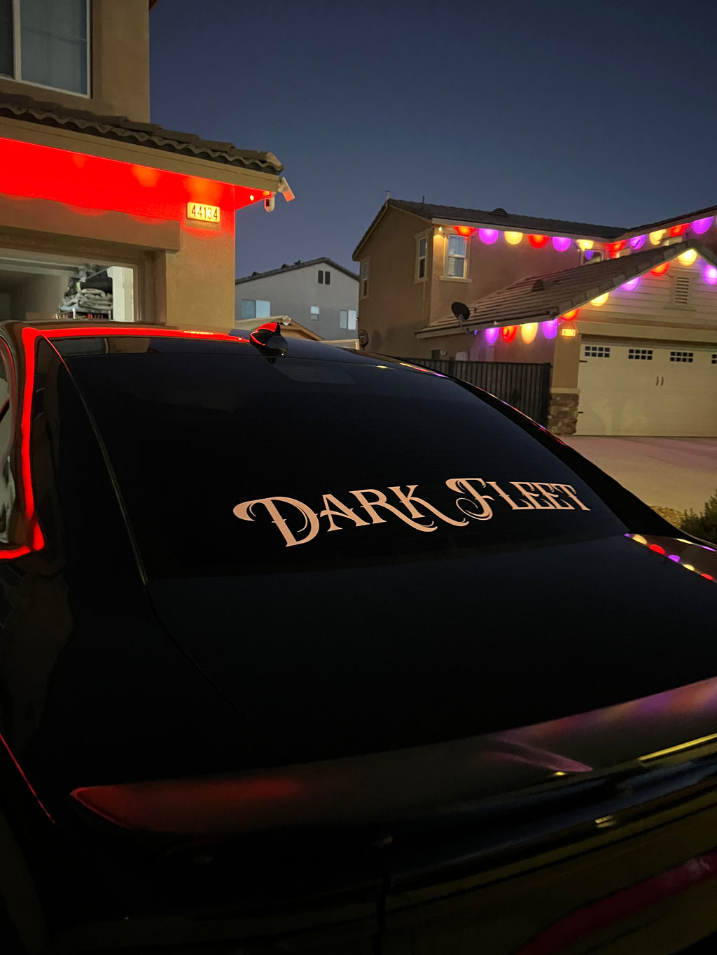 Car with 'Dark Fleet' logo on a residential street at night.