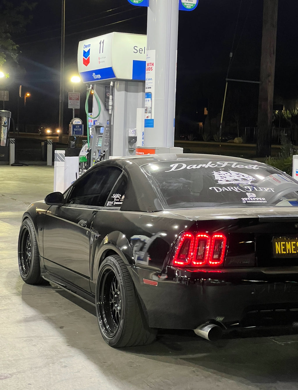 Black car with visible branding at a gas station at night