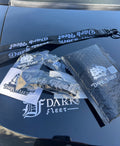 Dark Fleet merchandise including a lanyard, stickers, and a bubble-wrapped item on a car hood.